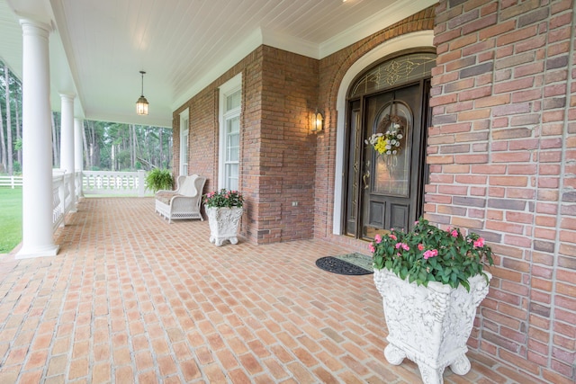 doorway to property featuring brick siding and a porch