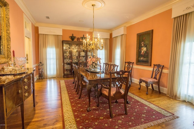 dining space with a chandelier, ornamental molding, baseboards, and wood finished floors