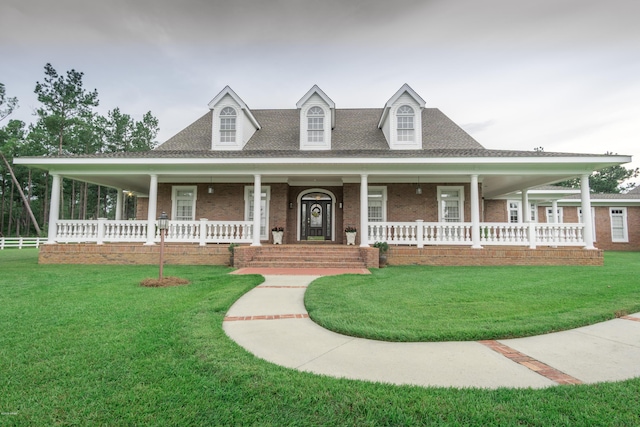 farmhouse with brick siding, a porch, a front lawn, and roof with shingles