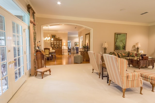 carpeted living area featuring visible vents, arched walkways, a notable chandelier, and ornamental molding