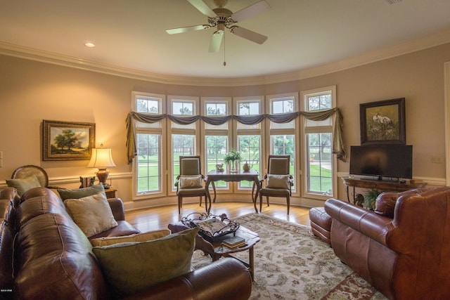 living area featuring a ceiling fan, crown molding, light wood-style floors, and baseboards