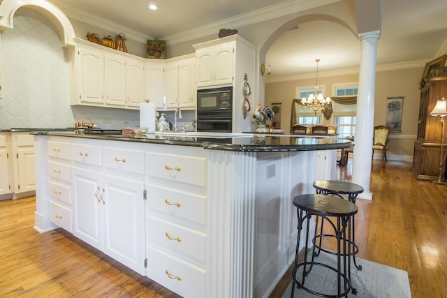 kitchen featuring white cabinets, black appliances, light wood-style floors, and ornamental molding