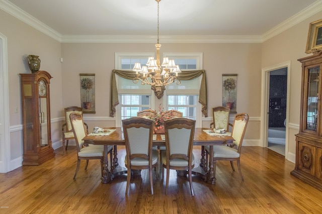 dining space with a chandelier, ornamental molding, and wood finished floors