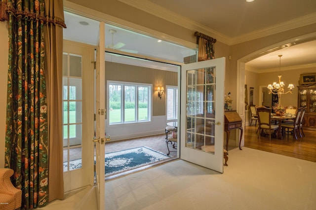 entryway featuring french doors, wood finished floors, a chandelier, and crown molding