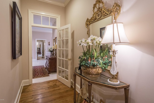 corridor with french doors, baseboards, wood finished floors, and ornamental molding