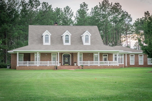 view of front facade with brick siding, a porch, and a front lawn