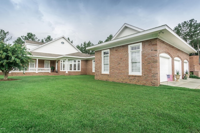 view of front of home with driveway, covered porch, an attached garage, a front yard, and brick siding