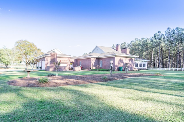 view of front of house with brick siding, a chimney, a front lawn, and fence