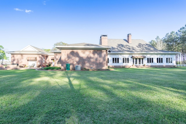 back of property featuring crawl space, a lawn, a chimney, and brick siding