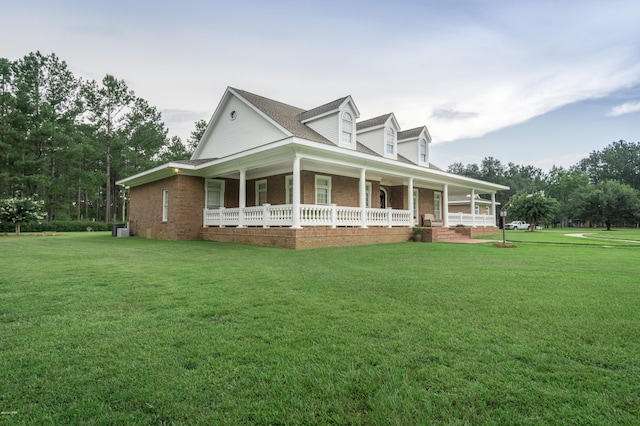 view of side of property with a yard, covered porch, and brick siding