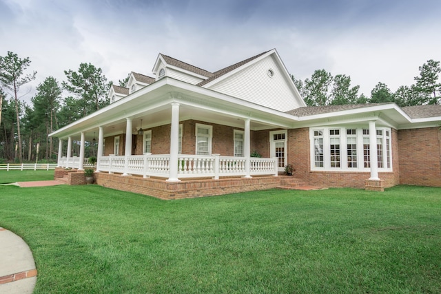 view of front of home featuring brick siding, a porch, a front yard, and fence