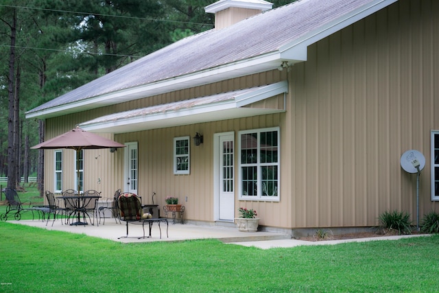 doorway to property with a lawn and a patio