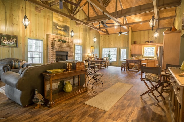 living area featuring a wealth of natural light, a brick fireplace, wood walls, and dark wood-style flooring