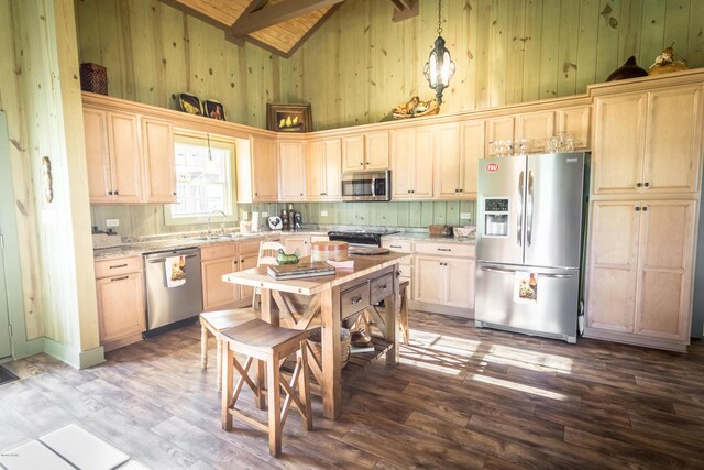 kitchen featuring beamed ceiling, high vaulted ceiling, a sink, wood finished floors, and appliances with stainless steel finishes