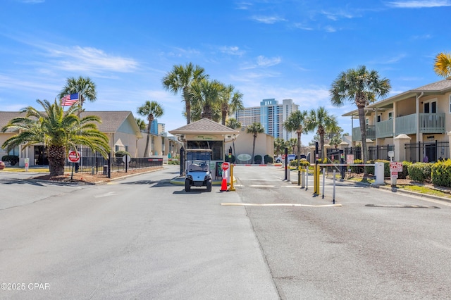 view of road with traffic signs, curbs, and a gated entry