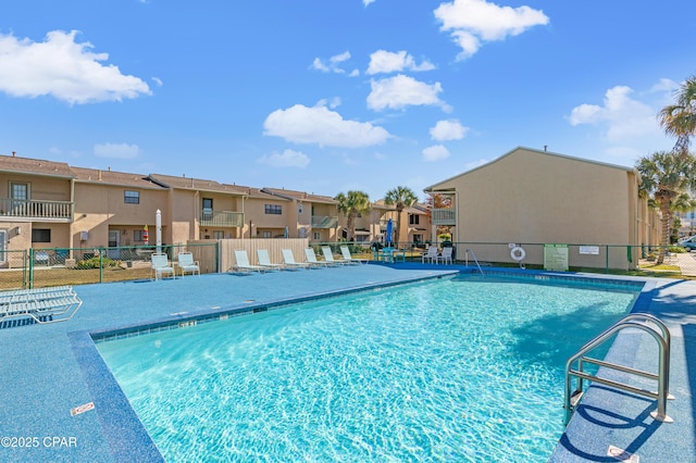 community pool with a patio area, a residential view, and fence