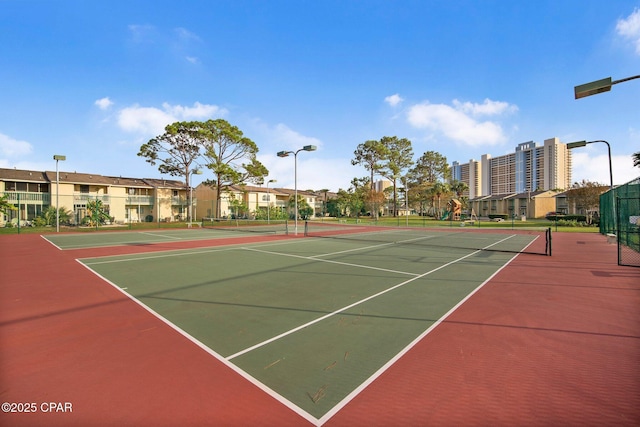 view of tennis court with community basketball court, fence, and a residential view