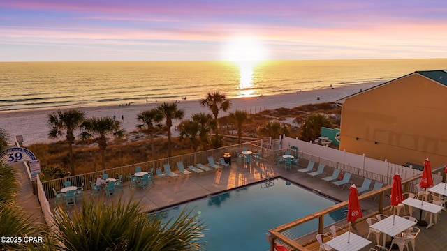 aerial view at dusk featuring a beach view and a water view