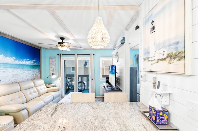 living area featuring beamed ceiling and ceiling fan with notable chandelier