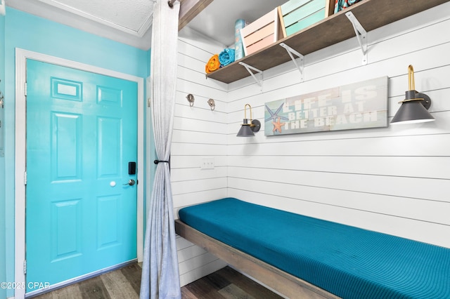 mudroom with a textured ceiling, wood finished floors, and wooden walls