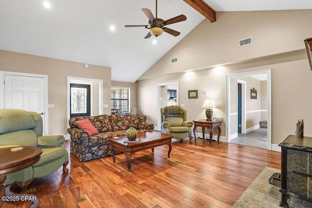 living area with high vaulted ceiling, light wood-style flooring, visible vents, and beamed ceiling