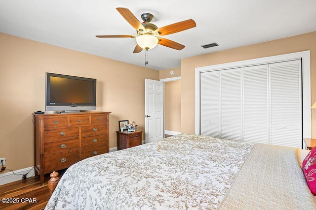 bedroom featuring ceiling fan, wood finished floors, visible vents, baseboards, and a closet