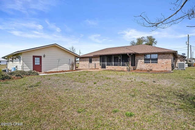 view of front of house with a sunroom, central AC unit, a front yard, and brick siding