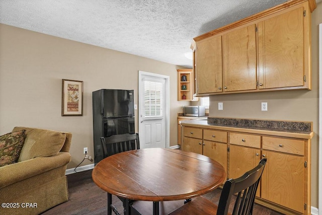 kitchen with stainless steel microwave, dark wood-style flooring, freestanding refrigerator, a textured ceiling, and open shelves