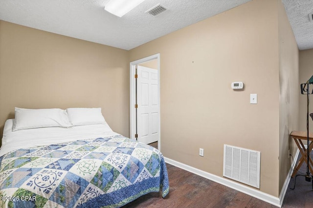 bedroom with baseboards, a textured ceiling, visible vents, and wood finished floors