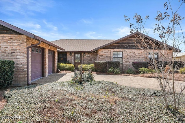 view of front of house with driveway, brick siding, an attached garage, and a shingled roof