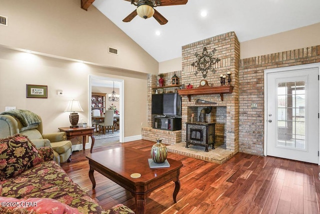 living room featuring visible vents, a ceiling fan, wood finished floors, a wood stove, and high vaulted ceiling