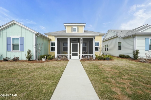 view of front facade featuring a front lawn, board and batten siding, and a sunroom