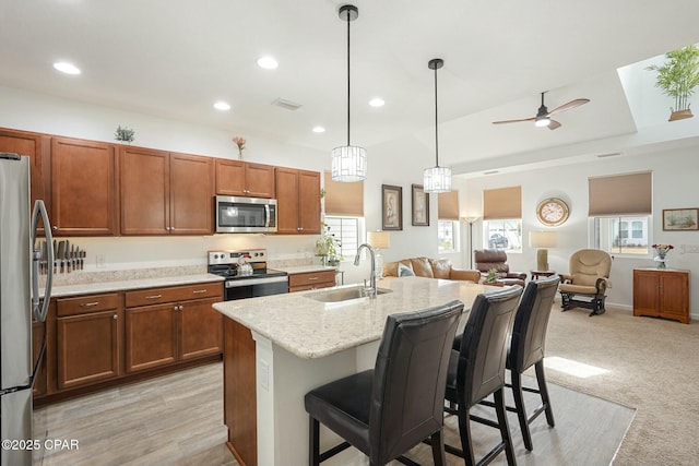 kitchen featuring a breakfast bar, a sink, visible vents, open floor plan, and appliances with stainless steel finishes