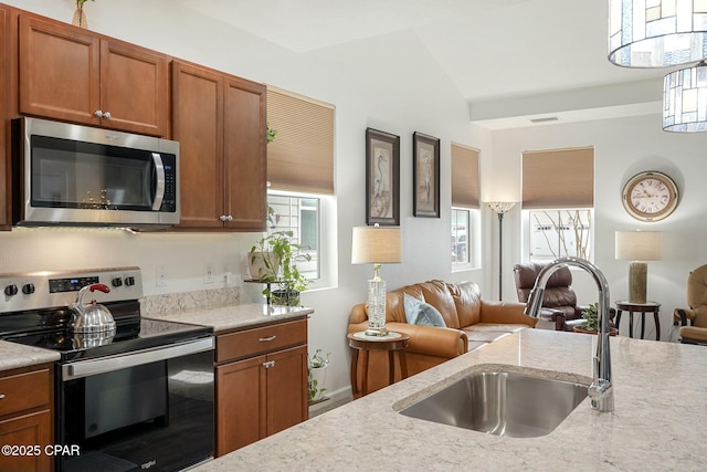 kitchen with plenty of natural light, appliances with stainless steel finishes, open floor plan, and a sink