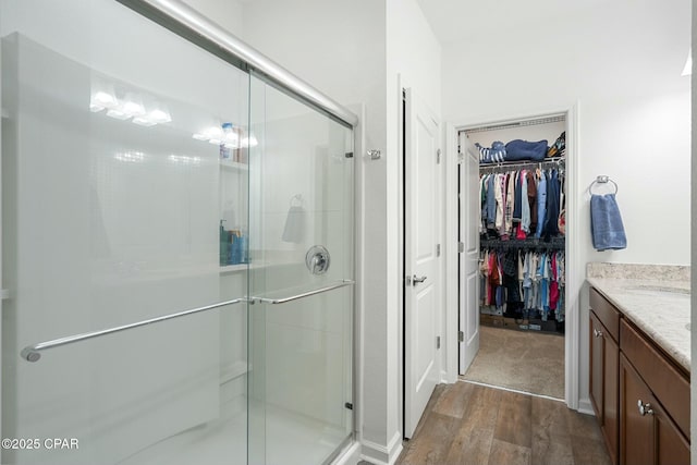 full bath with a shower stall, a spacious closet, wood finished floors, and vanity