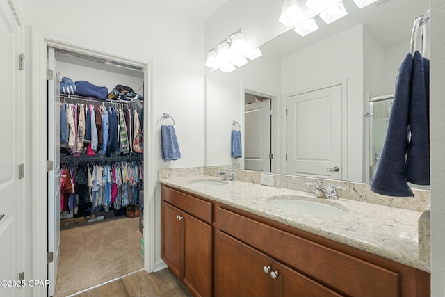 full bath with double vanity, a spacious closet, and a sink