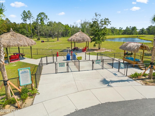 view of community with a water view, fence, a gazebo, a lawn, and a gate