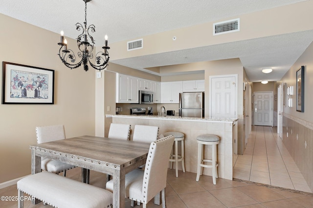 1160 Scenic Gulf Dr Unit A903, Miramar Beach, FL 32550 - dining room with light tile patterned floors, a notable chandelier, a textured ceiling, and visible vents
