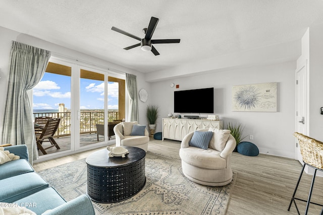 living room featuring a textured ceiling, a ceiling fan, and wood finished floors