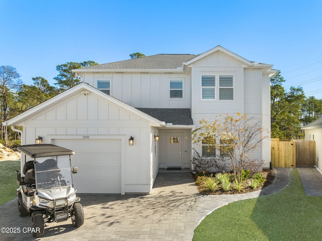 view of front of property featuring an attached garage, a shingled roof, fence, decorative driveway, and board and batten siding