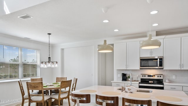 kitchen featuring stainless steel appliances, light countertops, crown molding, and tasteful backsplash