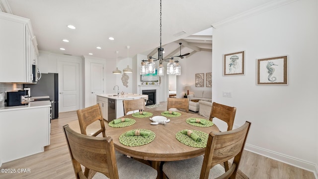 dining room with a fireplace, recessed lighting, ornamental molding, light wood-type flooring, and baseboards