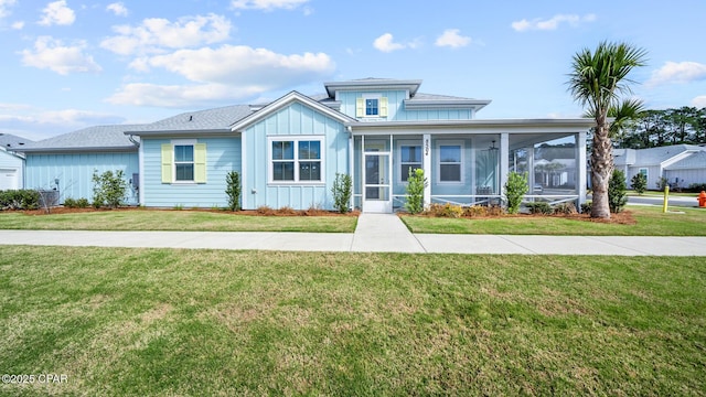 view of front of property featuring board and batten siding, a sunroom, and a front lawn