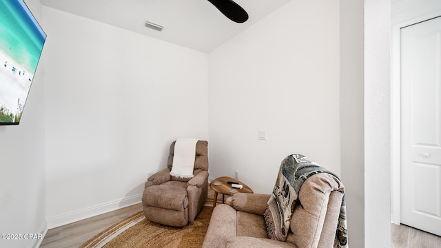 living area with a ceiling fan, baseboards, visible vents, and light wood finished floors