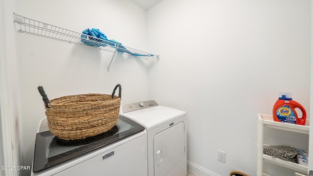 clothes washing area featuring laundry area, baseboards, and washing machine and clothes dryer