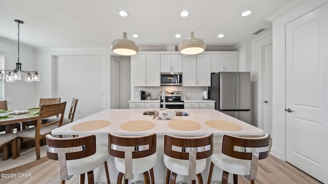 kitchen featuring a sink, light countertops, appliances with stainless steel finishes, decorative backsplash, and crown molding