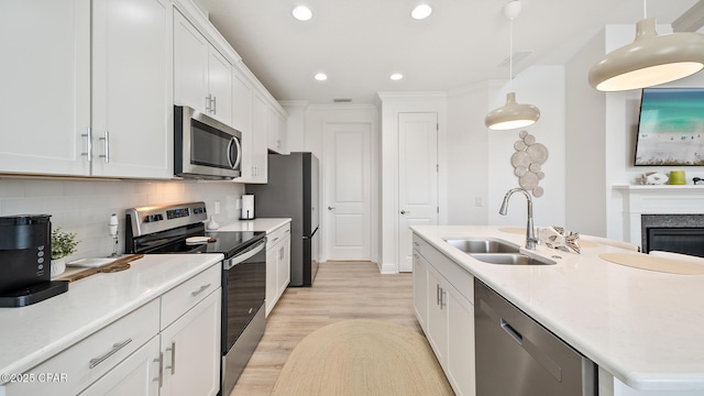 kitchen with decorative backsplash, appliances with stainless steel finishes, a kitchen island with sink, white cabinetry, and a sink