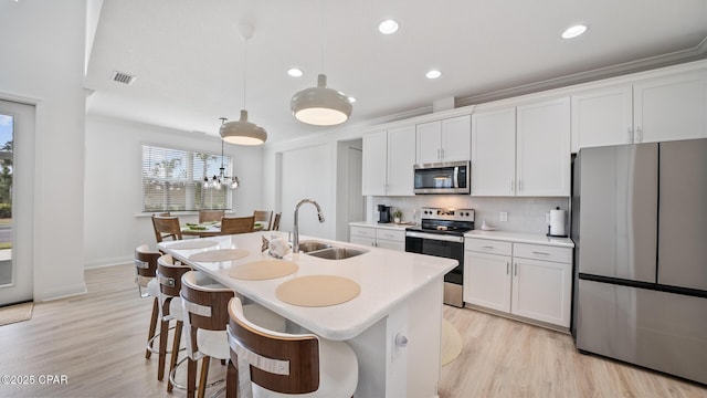 kitchen featuring a center island with sink, visible vents, appliances with stainless steel finishes, white cabinetry, and a sink