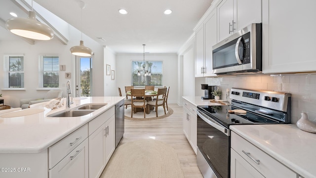 kitchen with white cabinets, a sink, stainless steel appliances, light countertops, and backsplash