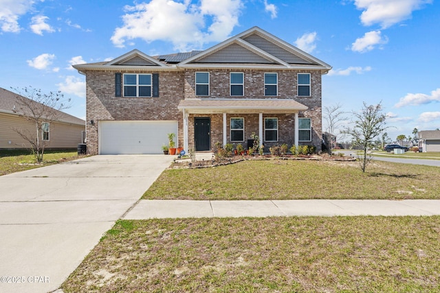 view of front facade with a garage, brick siding, concrete driveway, roof mounted solar panels, and a front yard